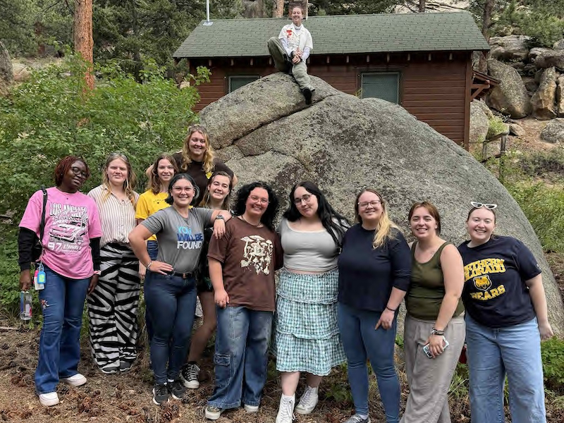 Students in front of large rock in the mountains. Student Honors Activities Council planning retreat.
