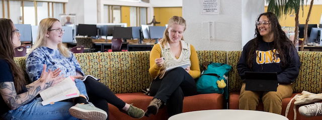 Four honors students conversing in the library