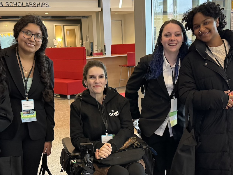 Group of four students in professional dress with conference name badges.