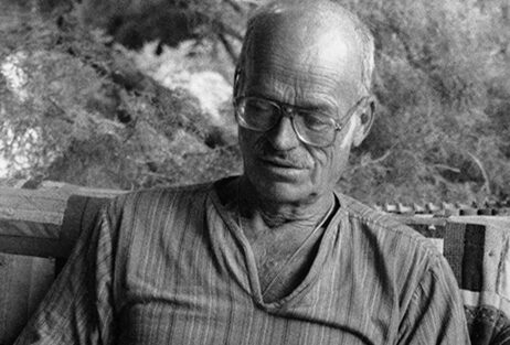 Photo of Robert O. Schulze reading a book at his home.