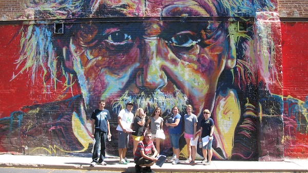 Group of students in front of a mural of Einstein.