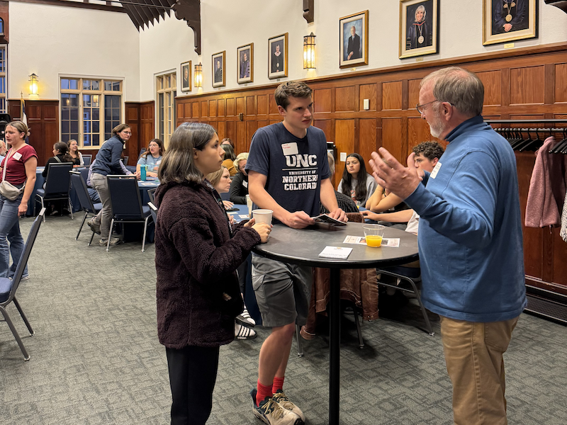 Professor talking to students around a small round table.