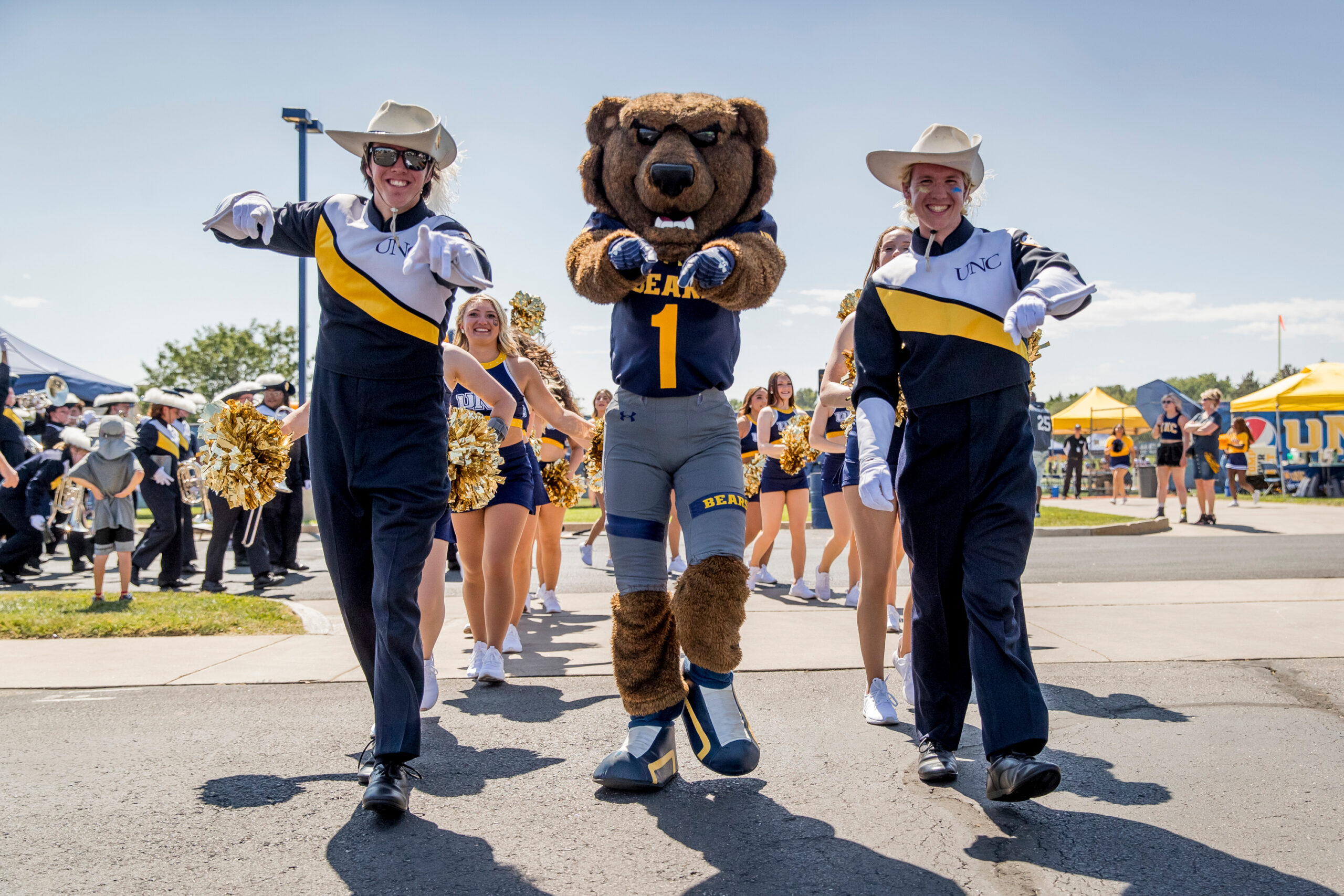 Klawz in the middle of two Pride of the Rockies members, all three pointing to the camera.