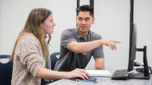 Two students are working on a computer.