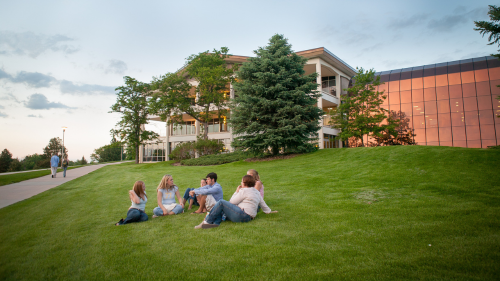 A group of students sit on the lawn in front of the University Center.