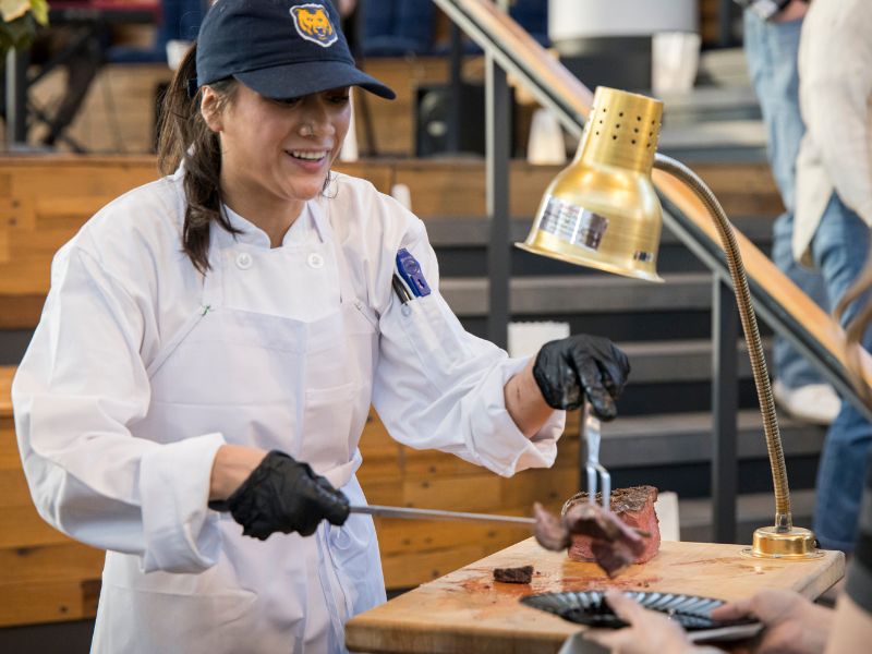 A member of the catering staff smiles as she serves someone at the carving station