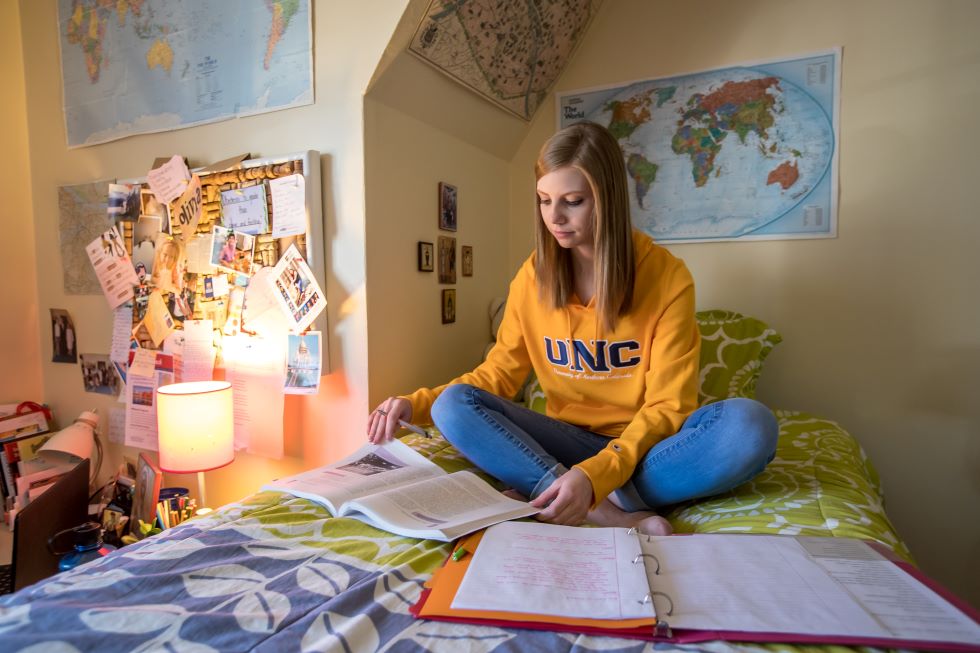 Student sitting on bed studying