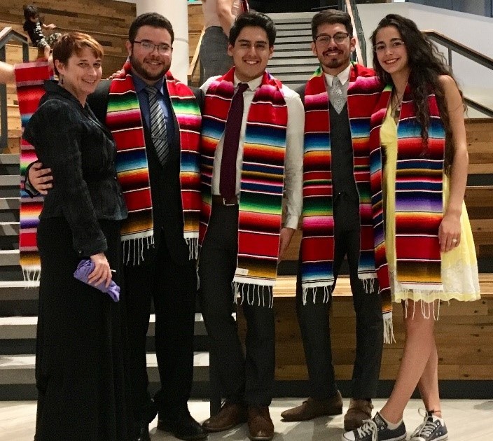Dr. Krista Caufman standing with 4 students wearing colorful sashes