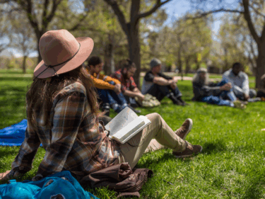 Students sit in a group with notebooks in front of them at Michener Quad
