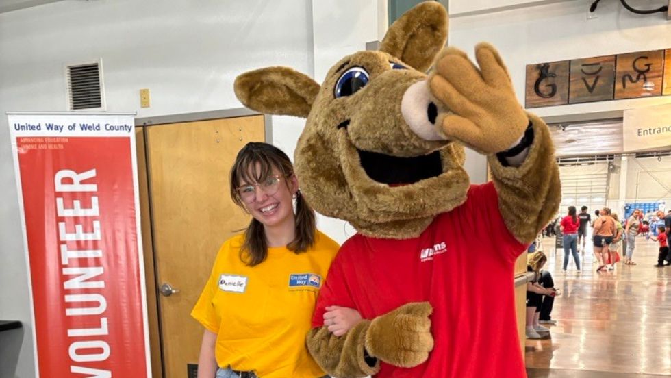 A PLP scholar poses with a mascot at an event