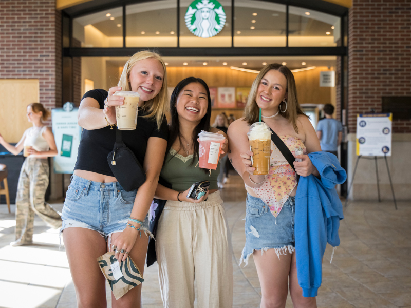 Three students enjoy a drink from Starbucks outside Holmes Dining Hall