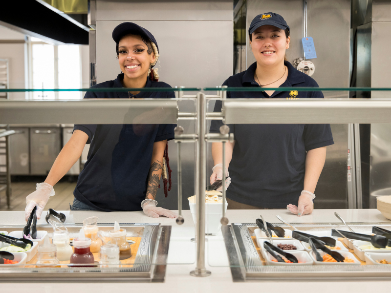 Two staff members serve food in Tobey-Kendel