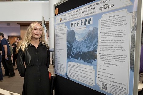Student standing in front of her poster presentation