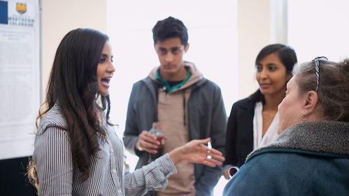 Female student explain her research to three others