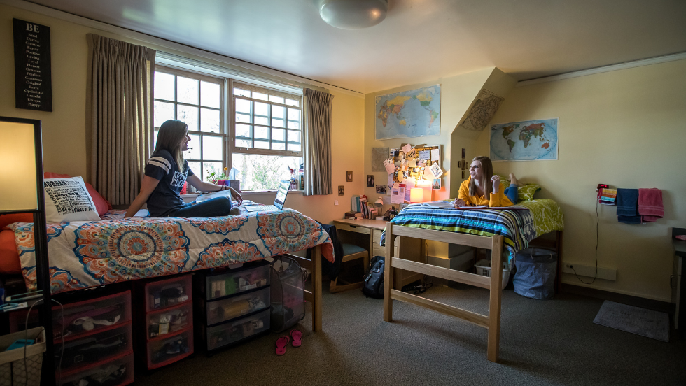Two roommates sit on their beds.