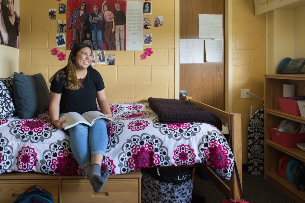 Student sitting on bed smiling