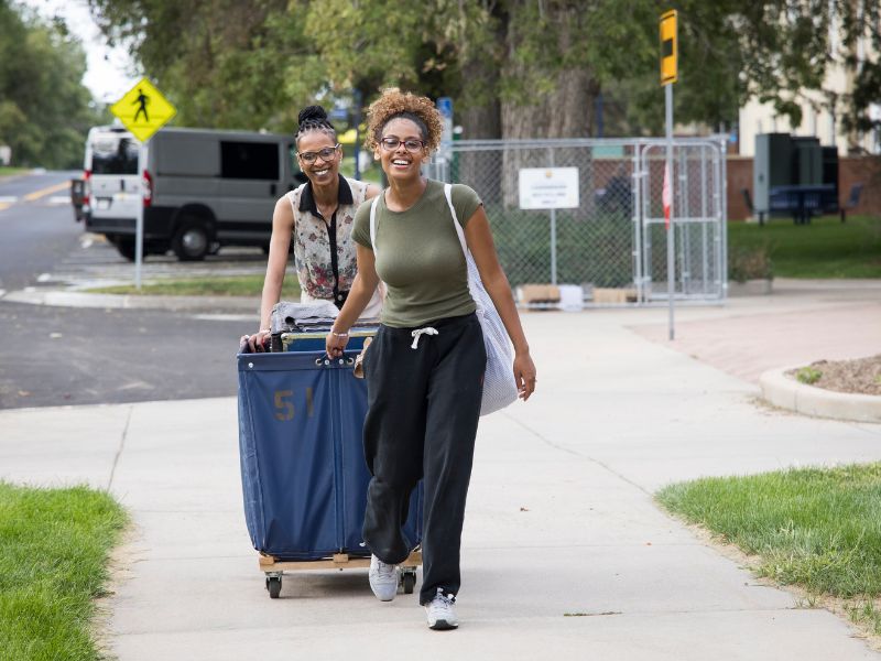 A student and her parent push a cart to her room