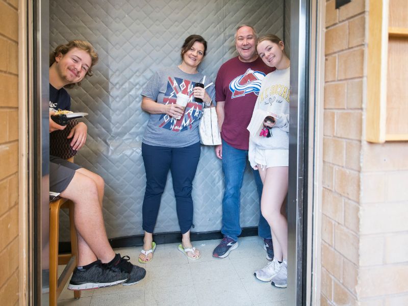 Students and parents smile for a photo in an elevator
