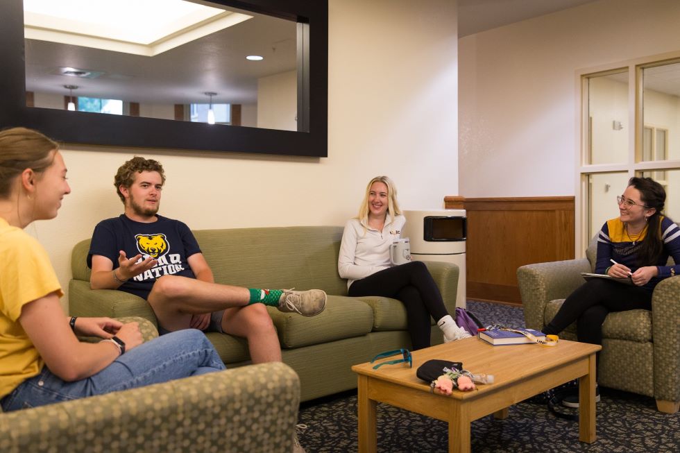 4 students sitting in hall lounge chatting