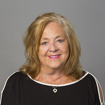 A woman with blonde hair, dressed in a black shirt. Smiling for a picture.