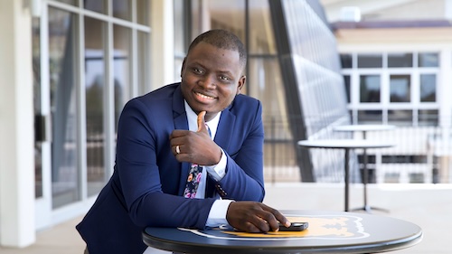 International graduate student smiling and giving a thumbs up