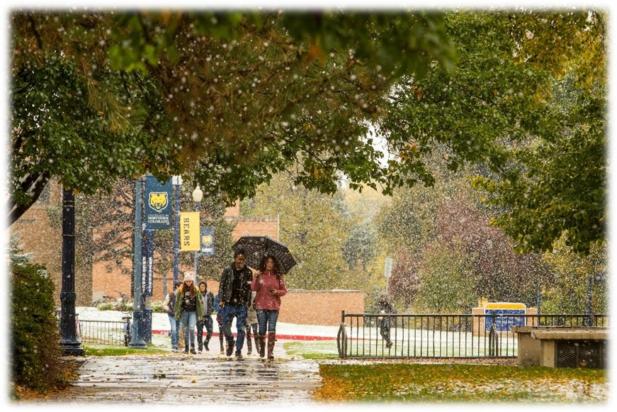 People walking on campus while it is snowing.