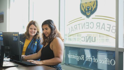 A member of the Registrar staff helps a student on the computers in Bear Central.