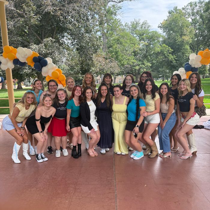 Members of Panhellenic pose for a group photo under balloon arches