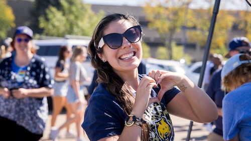 UNC student making a heart with her hands while wearing a UNC shirt Female student in UNC shirt forming a heart shape with her hands