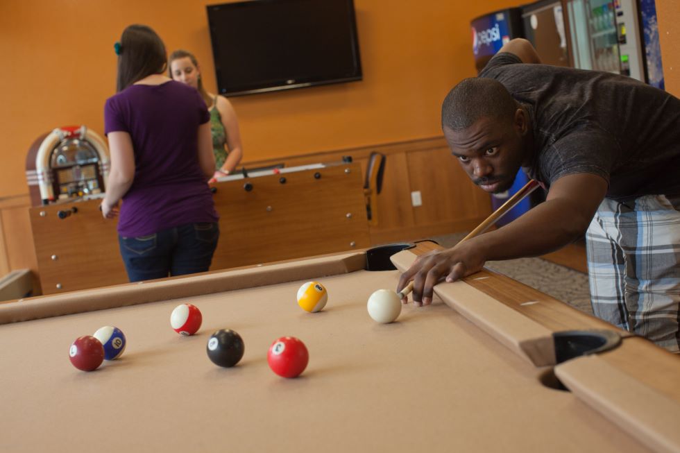 Students playing pool and foosball