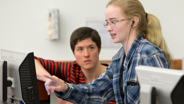 Student at computer being helped by library faculty member.