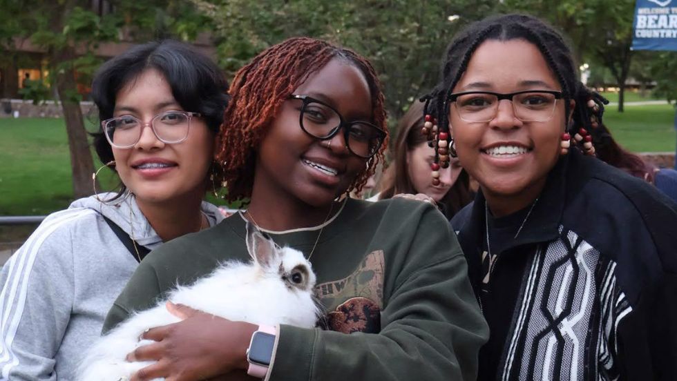 Students pose with a bunny at a petting zoo event.