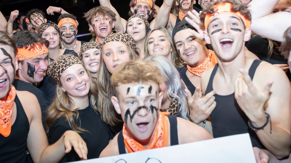 A large group of students pose for a group photo while wearing matching outfits.