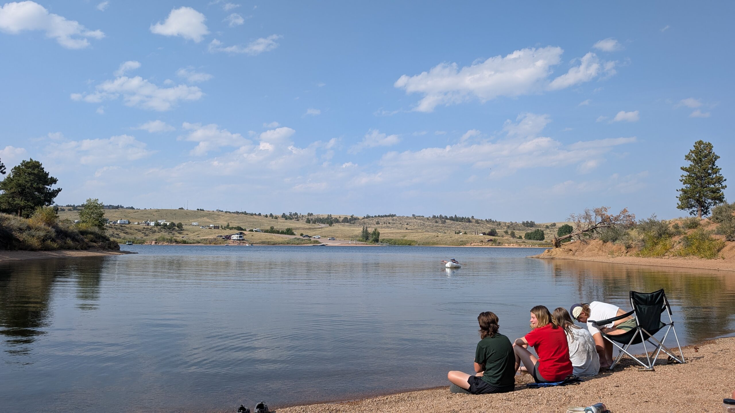 Four students at the Wyoming Camping trip, sitting in front of a lake.