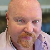 A man with green eyes, smiling for a photo 