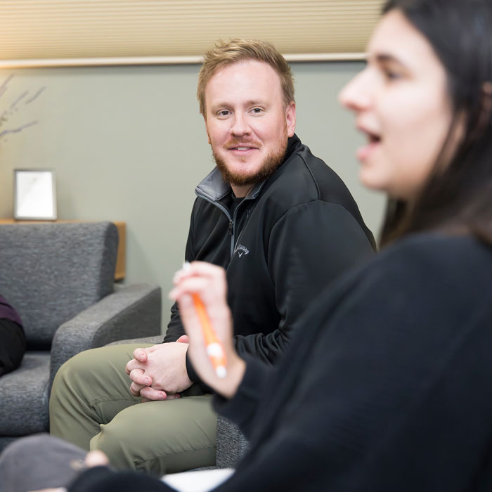 Graduate counseling student looking another student as they are talking.
