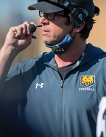 UNC football coach Ed McCaffrey talking into a headset.