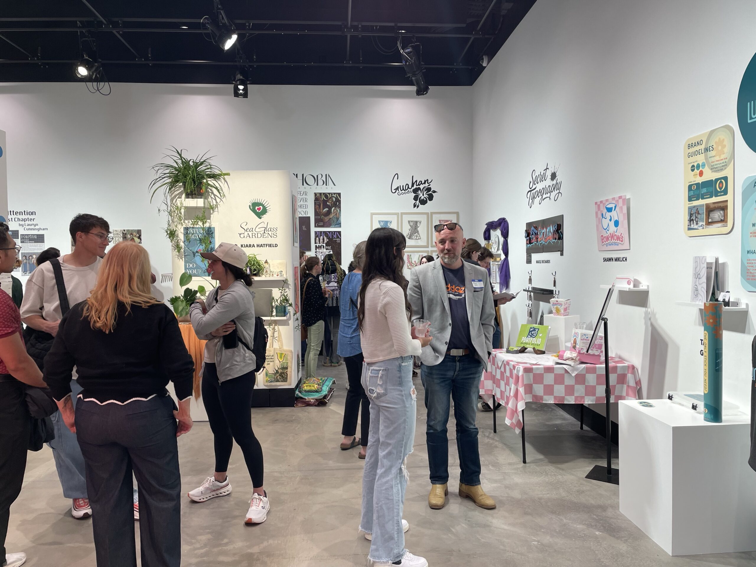 People viewing artwork at the Graphic Design Senior Show.