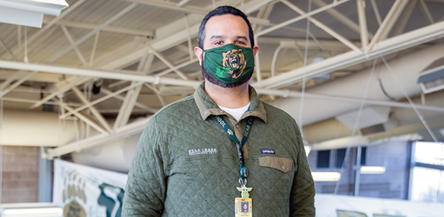 UNC alumnus Jose Martinez posing for the camera while standing in a high school gym.