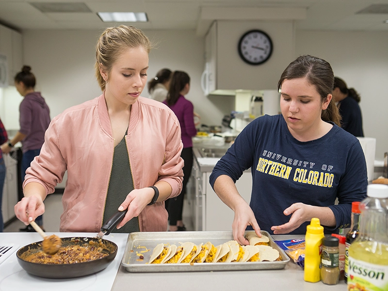 Two student cooking in test kitchen.