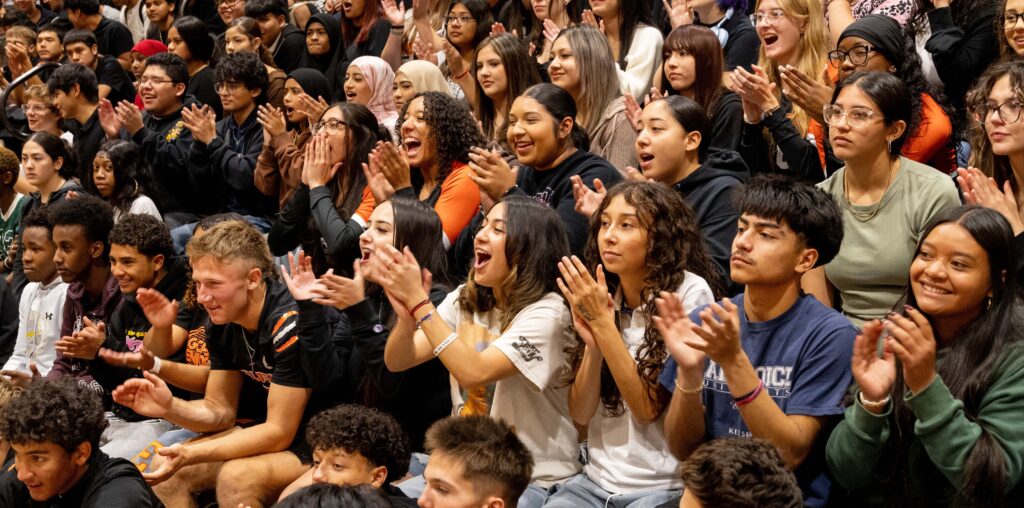 A crowd of students at an assembly cheering