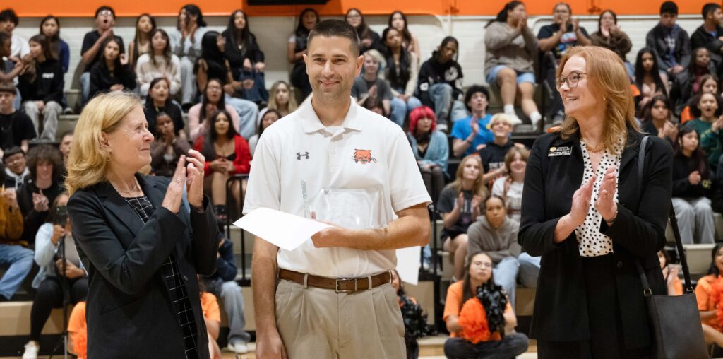 Stephen Paulson standing between two woman at an assembly