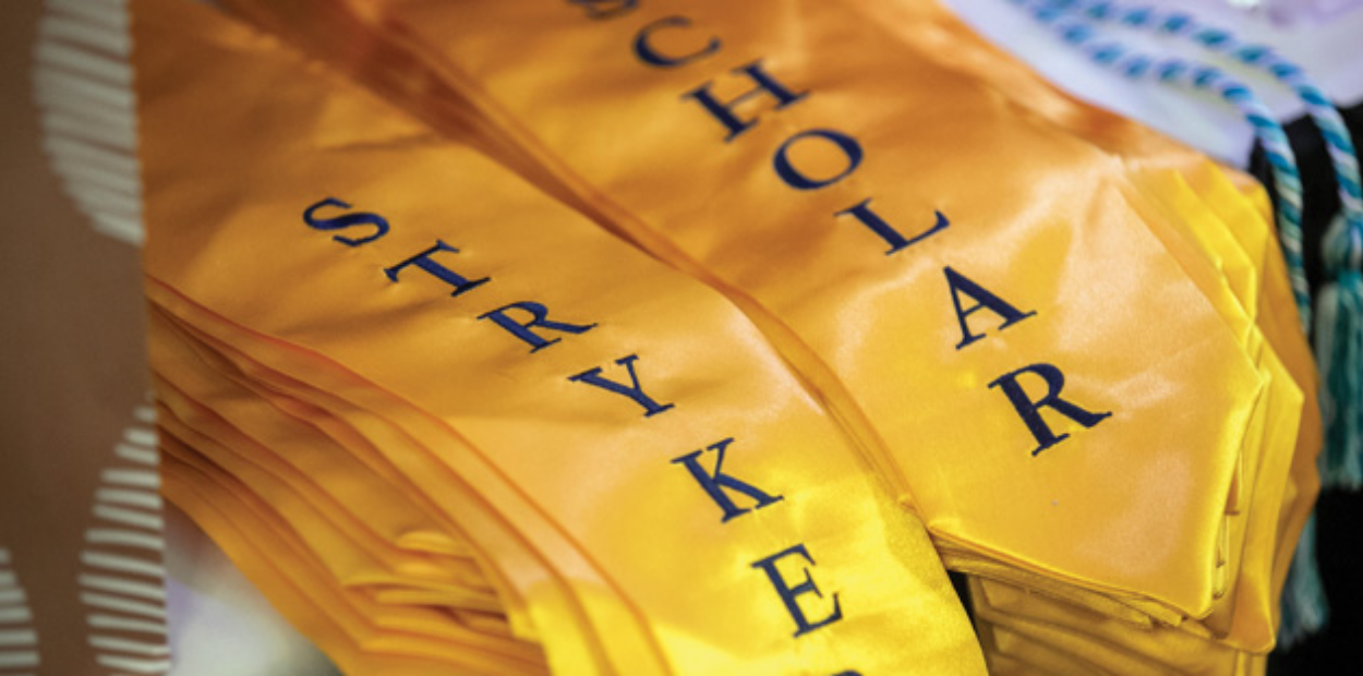 A close-up image of a stack of graduation stoles with the words 