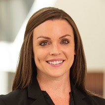 A woman smiling, dressed in a black shirt with a light background.