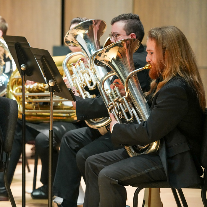 Brass players in the UNC Wind Ensemble playing on stage.