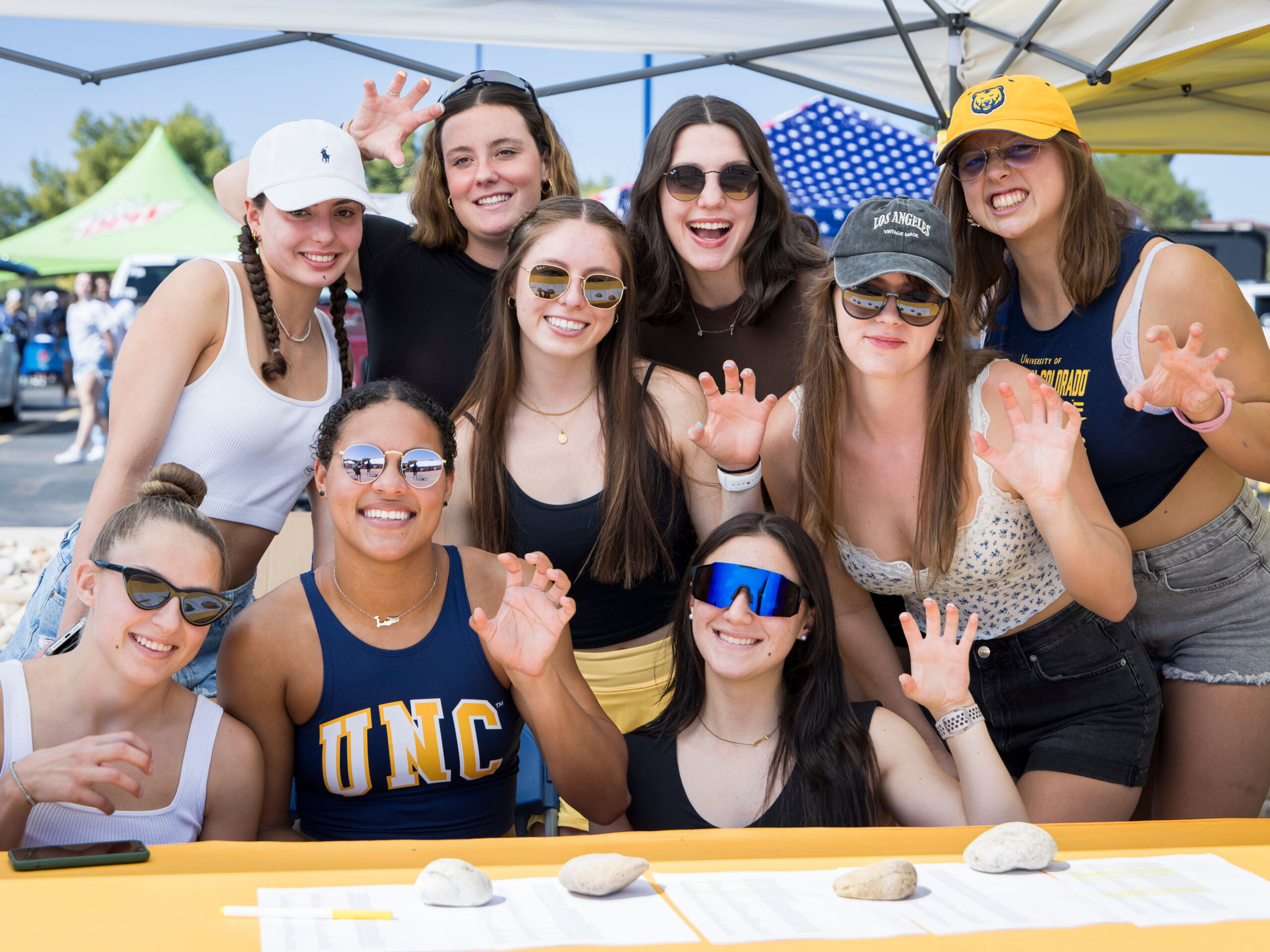 A group of UNC female students smiling and making a bear claw out of their hand.