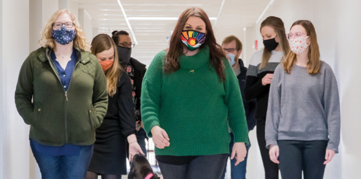 Professor Erin Yosai and a group of students walking down a hallway.