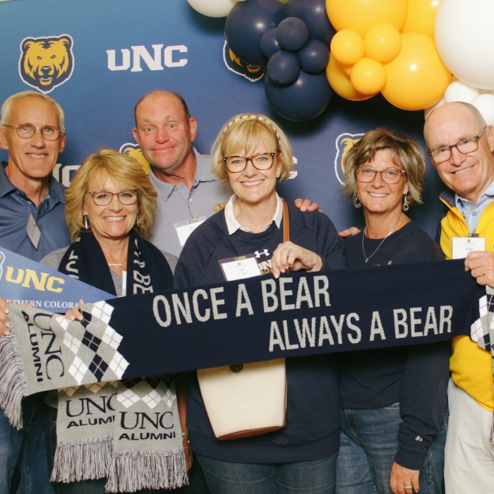 Group of UNC alumni at All Alumni Social holding a scarf that says, 