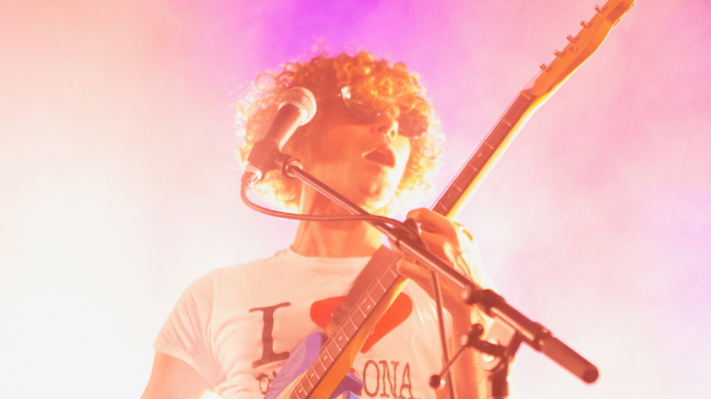 A musician playing the guitar and wearing sunglasses