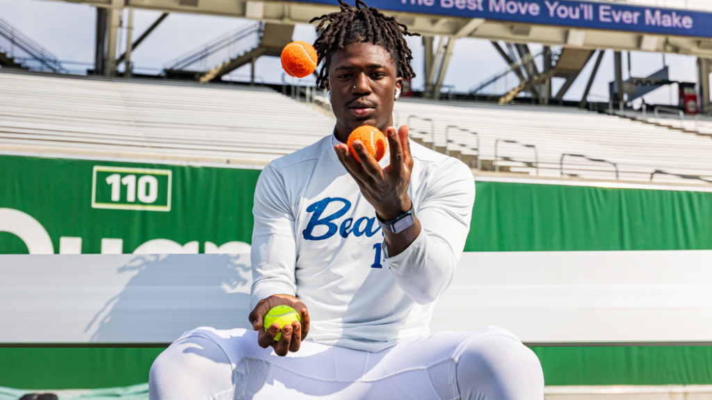 A UNC baseball player juggling tennis balls that are orange and yellow